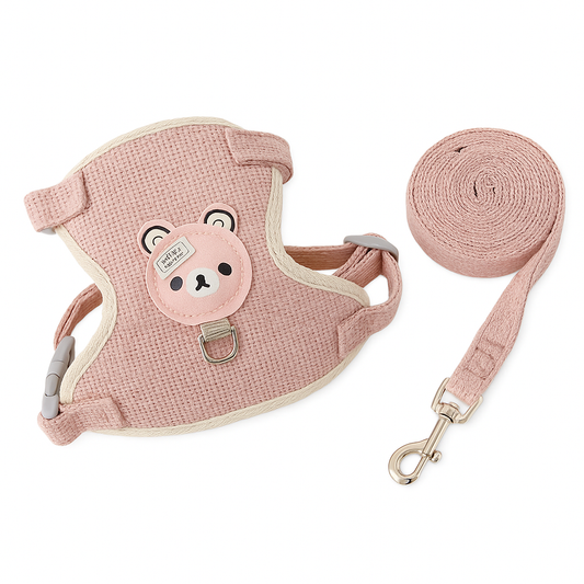 Pink pet harness with a cute bear patch and matching coiled leash, both made of soft textured fabric.